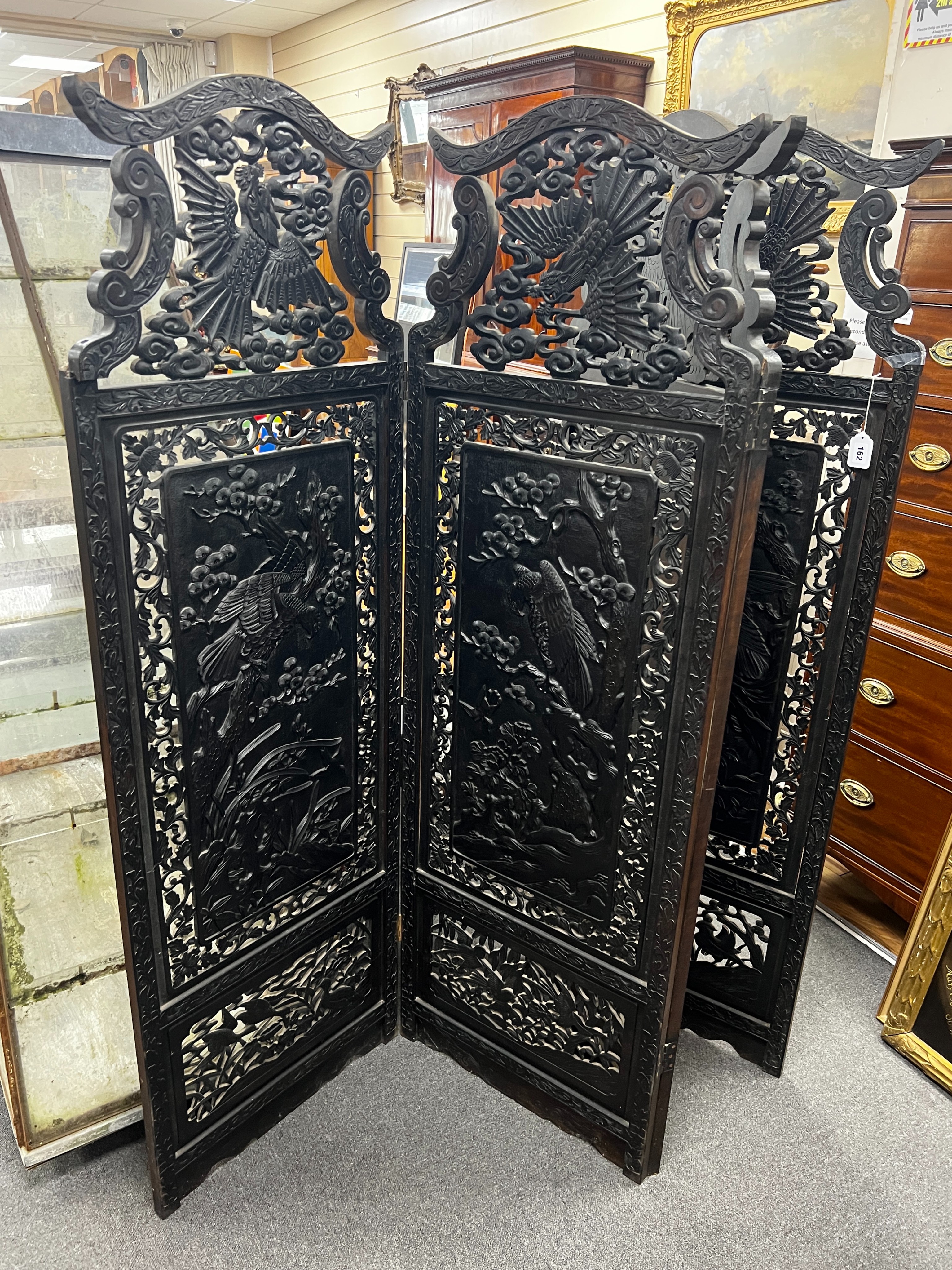 An early 20th century Japanese carved ebonised wood four fold dressing screen, width 56cm, height 173cm